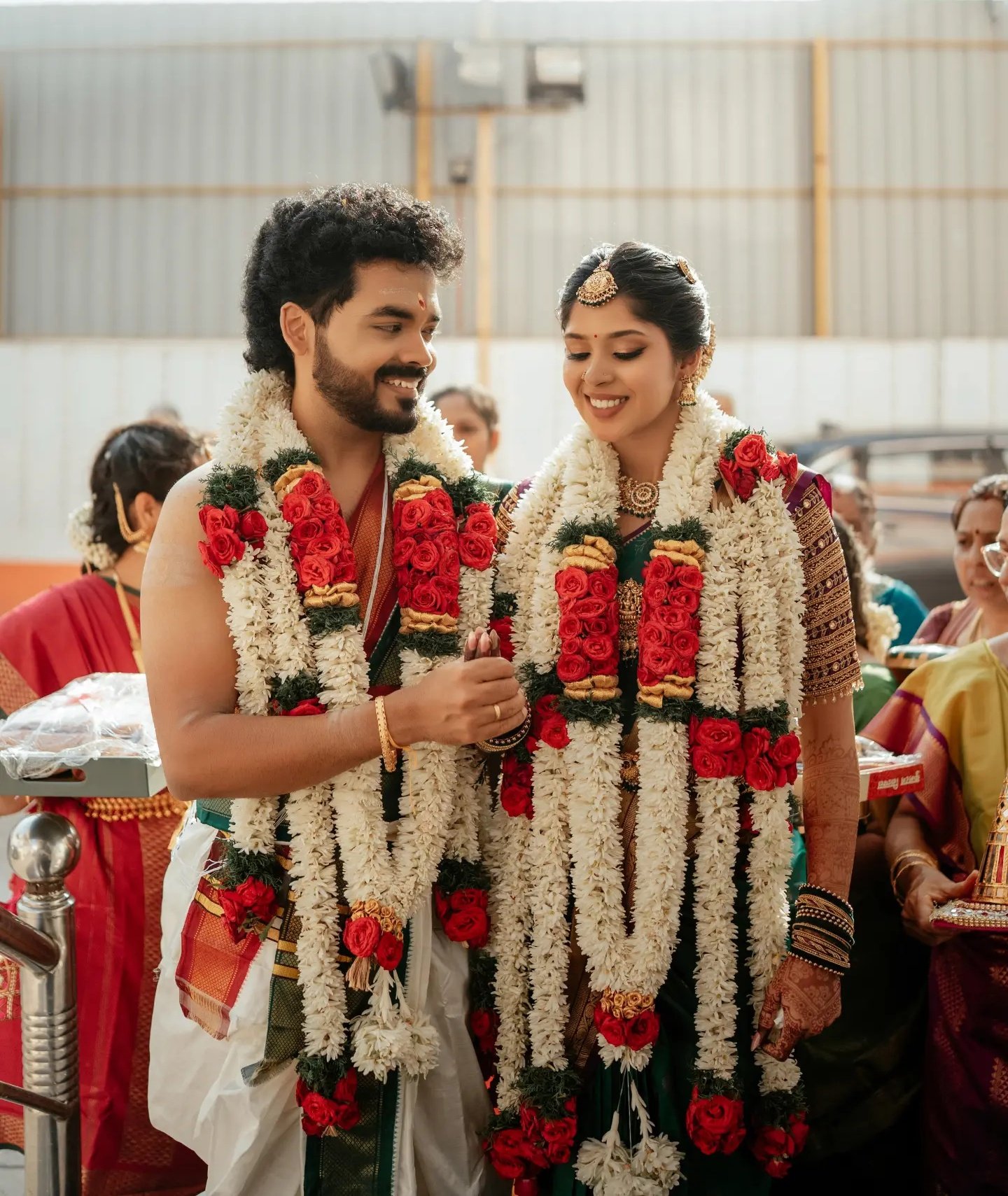 A bride in traditional crimson silk saree illuminated in temple doorway